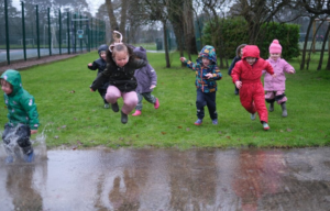 young children jumping into puddles